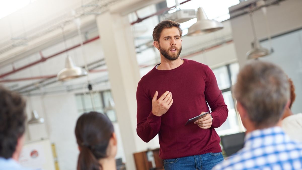 Man confidently speaking to his team of colleagues, demonstrating strong business communication skills