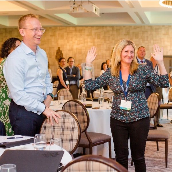 Two professionals smiling and practising confident body language techniques with arms wide open during a Project Charisma corporate public speaking training workshop at the CII conference in Glasgow