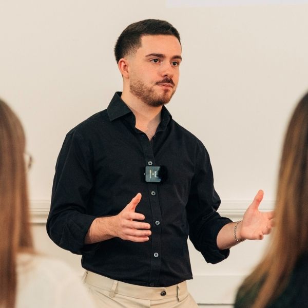 Male client confidently presenting and gesturing to a group during a Project Charisma 1-to-1 public speaking coaching workshop in Manchester