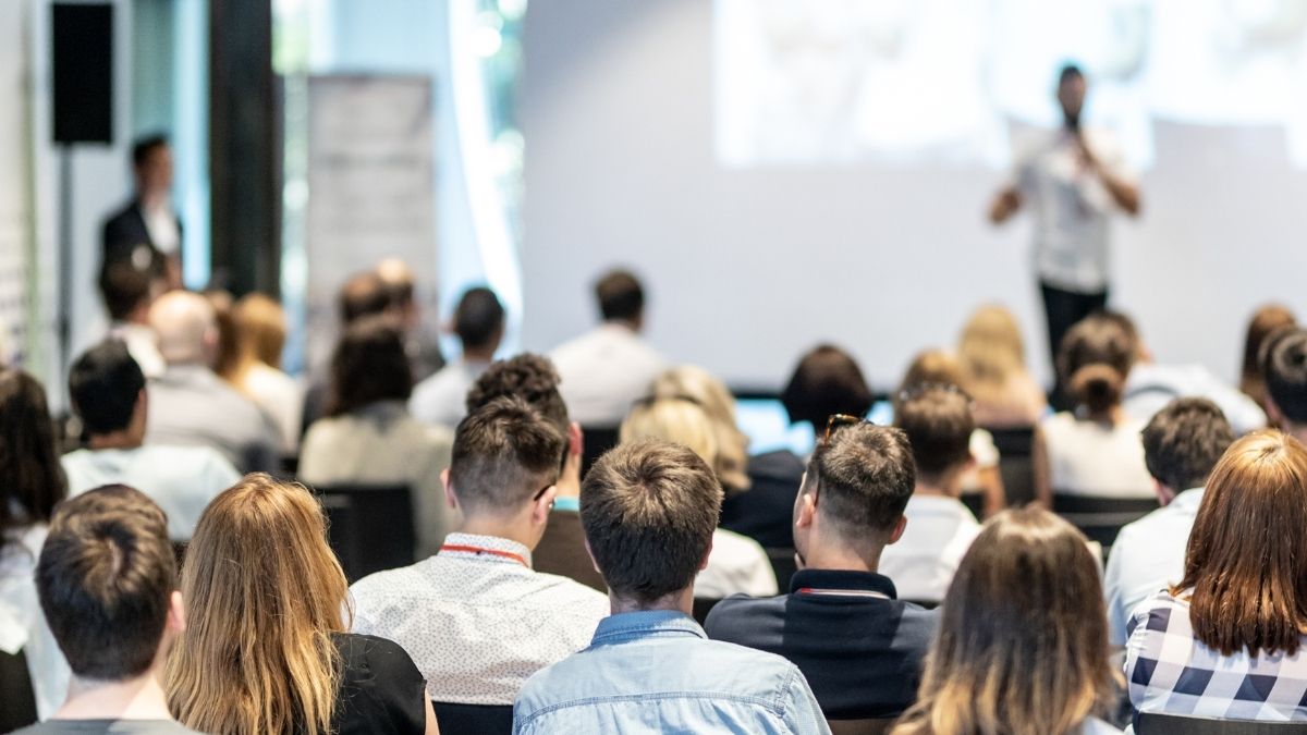 Speaker delivering an engaging paid talk at a conference to an audience of potential prospects