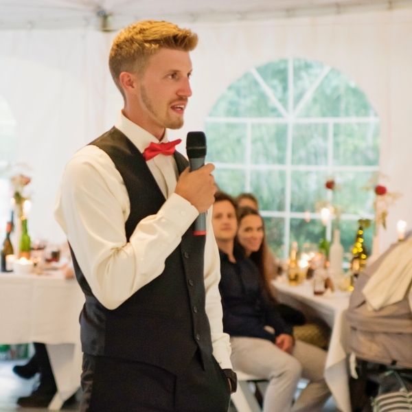 Best man confidently delivering his speech in front of wedding guests without notes.
