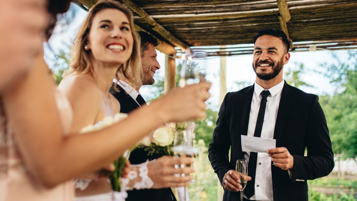 Best man smiling confidently while delivering his best man speech at a wedding reception