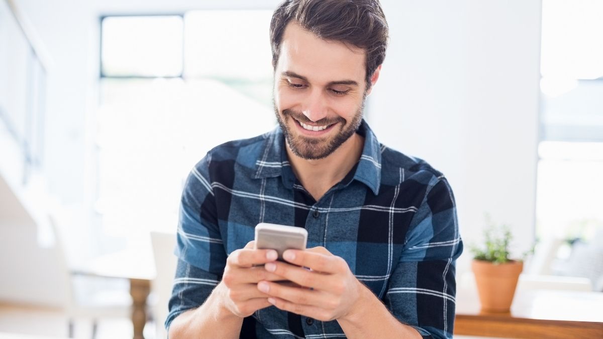 Man smiling while searching for the best public speaking apps on his smartphone