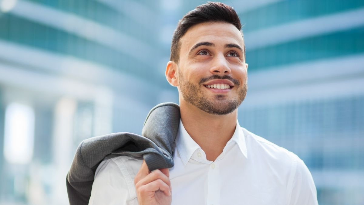 Man in a suit walking and smiling after building confidence in his public speaking skills