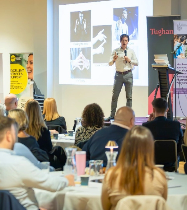 Ed Darling delivering his keynote talk "Speaking with Impact" on stage at a large professional conference in Belfast