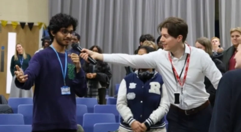 Ed Darling holding a microphone for a student speaking to a large audience during public speaking training at Ashton 6th Form College apprenticeship event