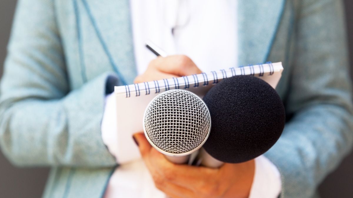 Man holding a microphone and notepad while trying to figure out how to write a speech