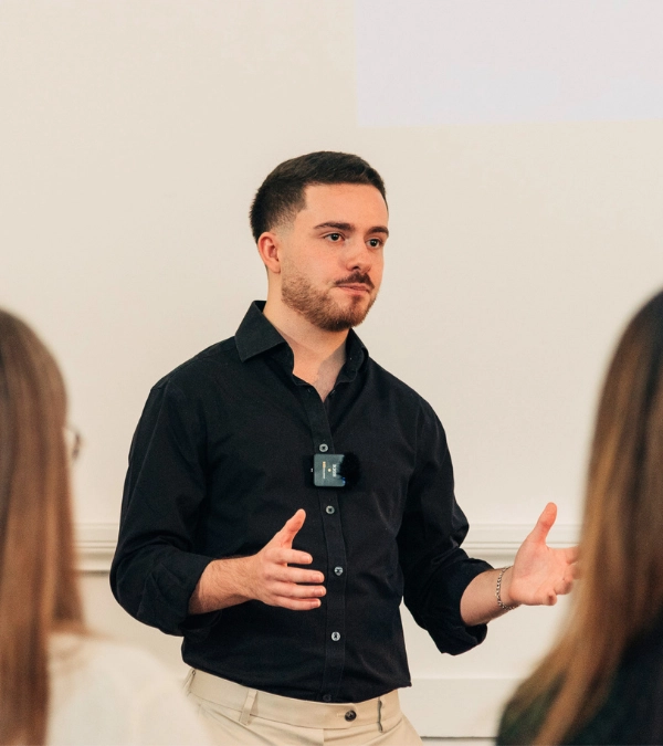 Male client confidently presenting and gesturing to a group during a Project Charisma 1-to-1 public speaking coaching workshop in Manchester