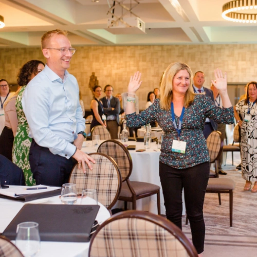 Two professionals smiling and practising confident body language techniques with arms wide open during a Project Charisma corporate public speaking training workshop at the CII conference in Glasgow