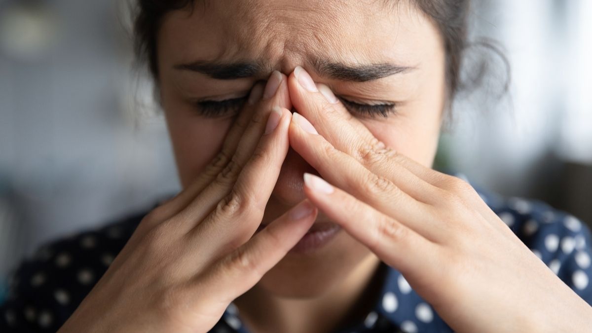 Woman with her head in her hands, looking stressed and lacking confidence due to a toxic workplace environment
