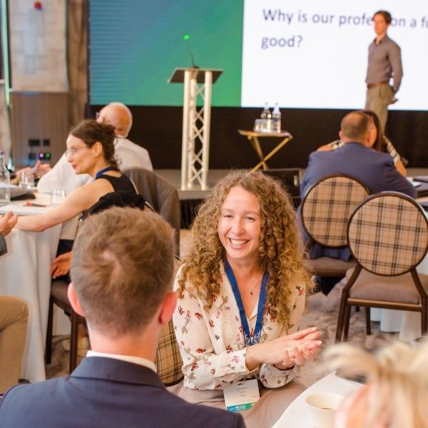 Woman smiling during an in-person public speaking training session at a corporate conference